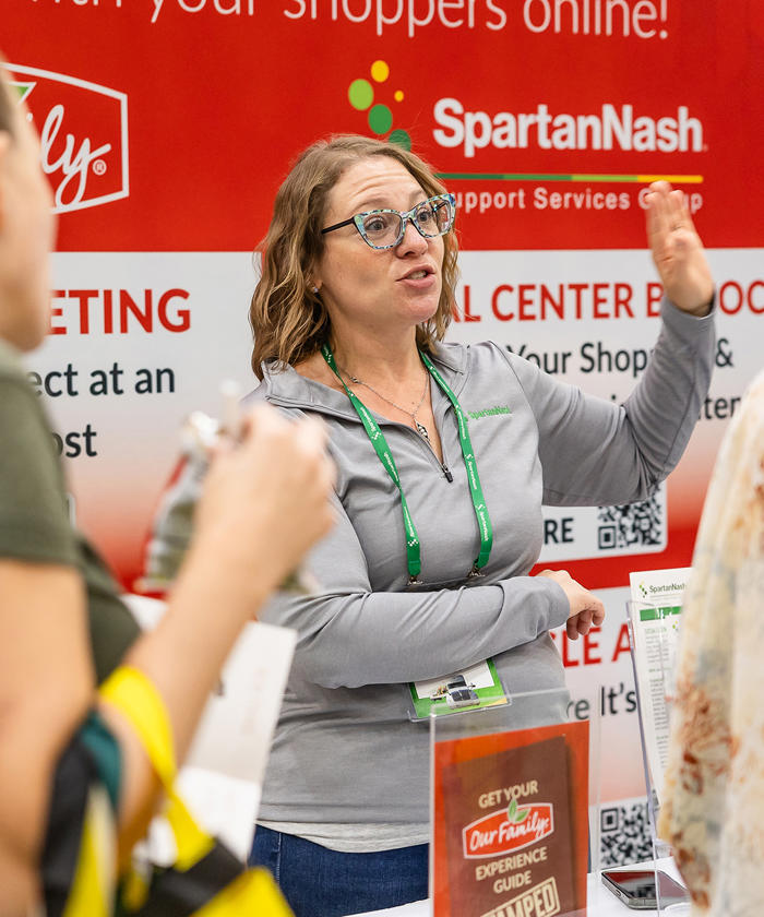 a woman standing in front of a sign at a Own Brands marketing event