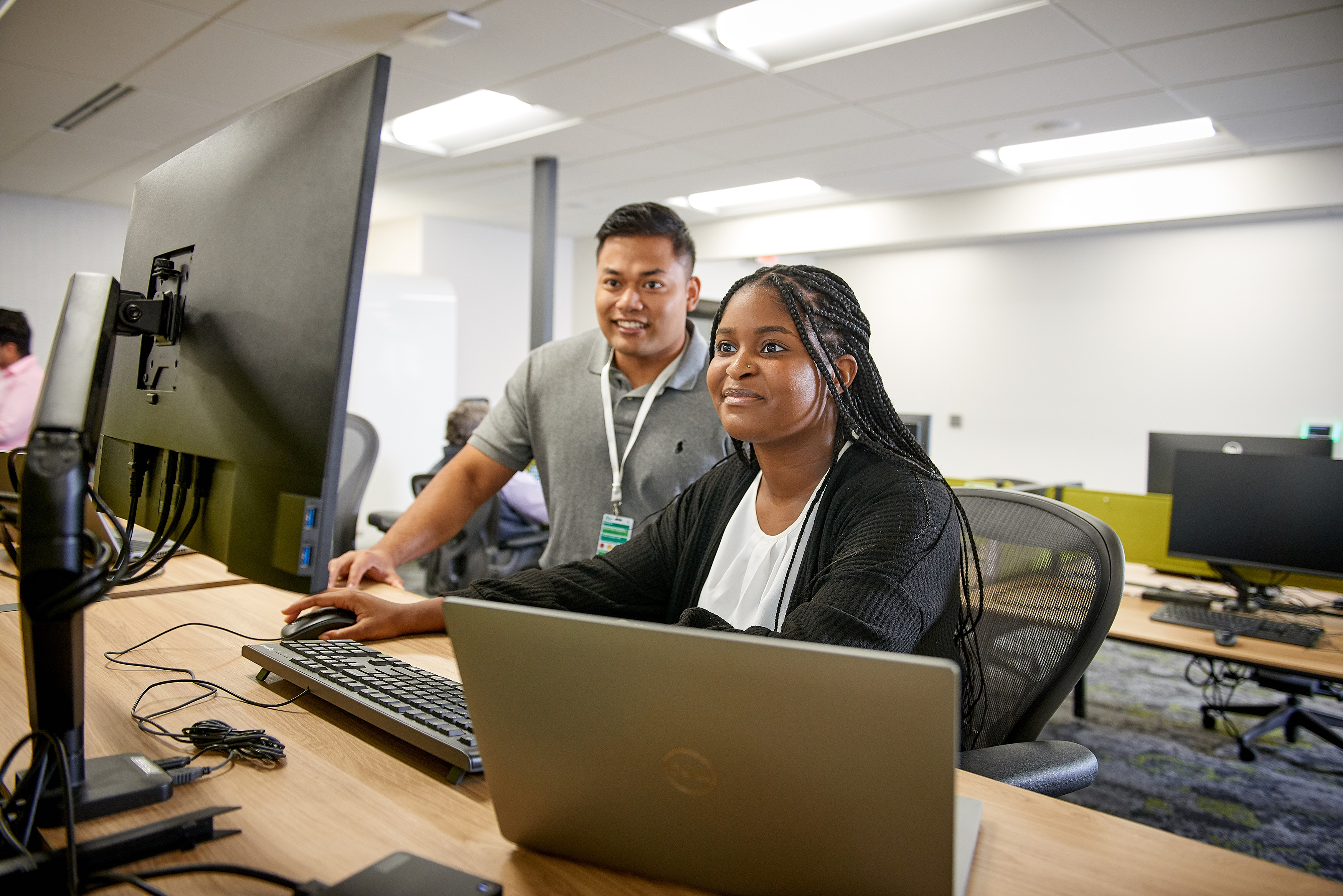 a man and woman sitting at a desk with computers