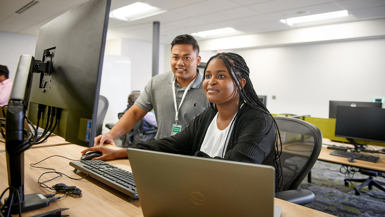 a man and woman sitting at a desk with computers