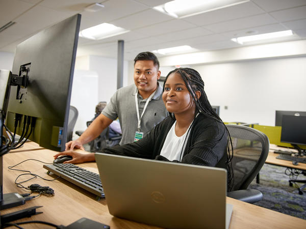 a man and woman sitting at a desk with computers