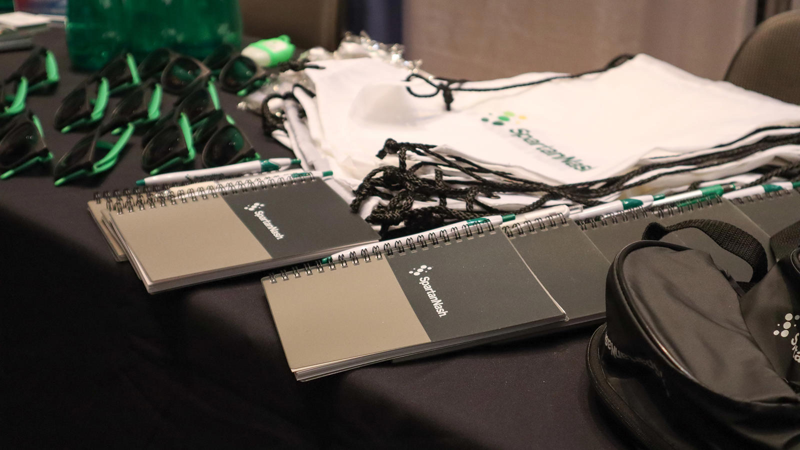 a table with notebooks and a bag at a SpartanNash employment event