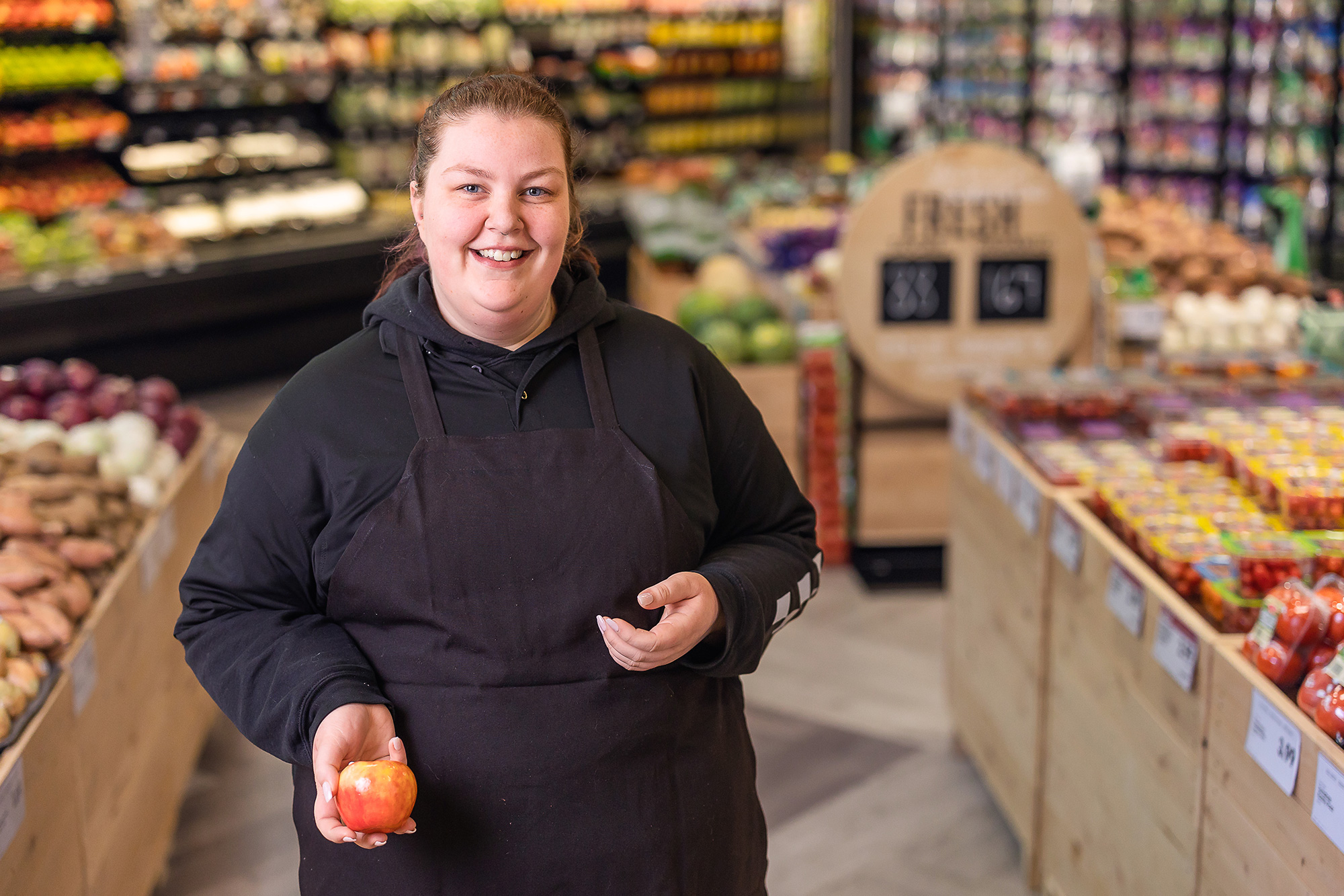 a woman holding an apple in the D&W at Knapps Corner grocery store