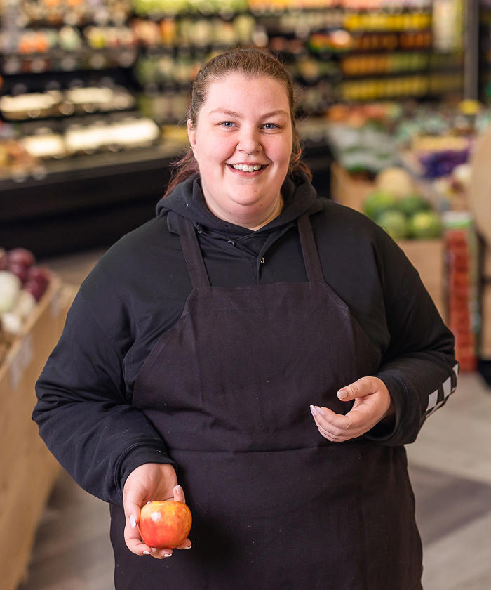a woman holding an apple in the D&W at Knapps Corner grocery store