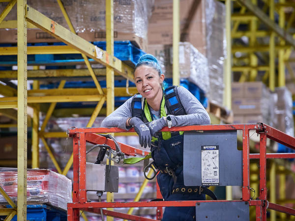 a woman leaning on a metal structure in a SpartanNash distribution center