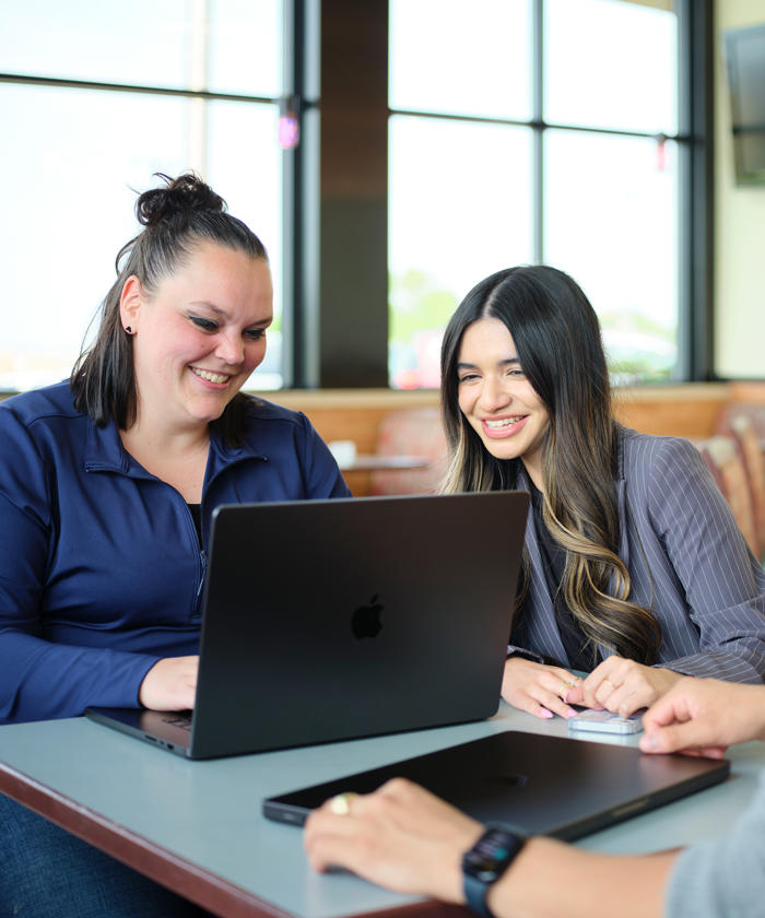 a group of people sitting at a table looking at a laptop