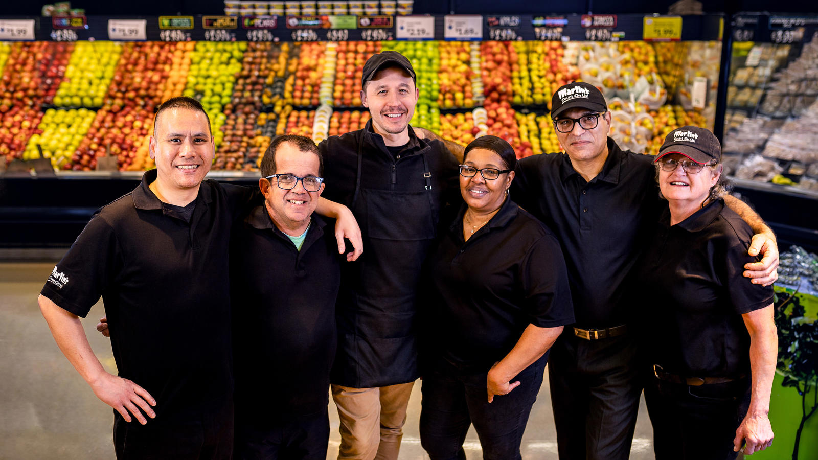 a group of people posing for a photo in a SpartanNash grocery store