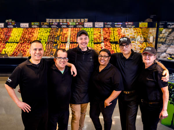 a group of people posing for a photo in a SpartanNash grocery store