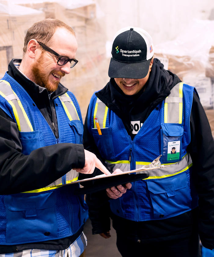 a man in safety vests looking at a tablet