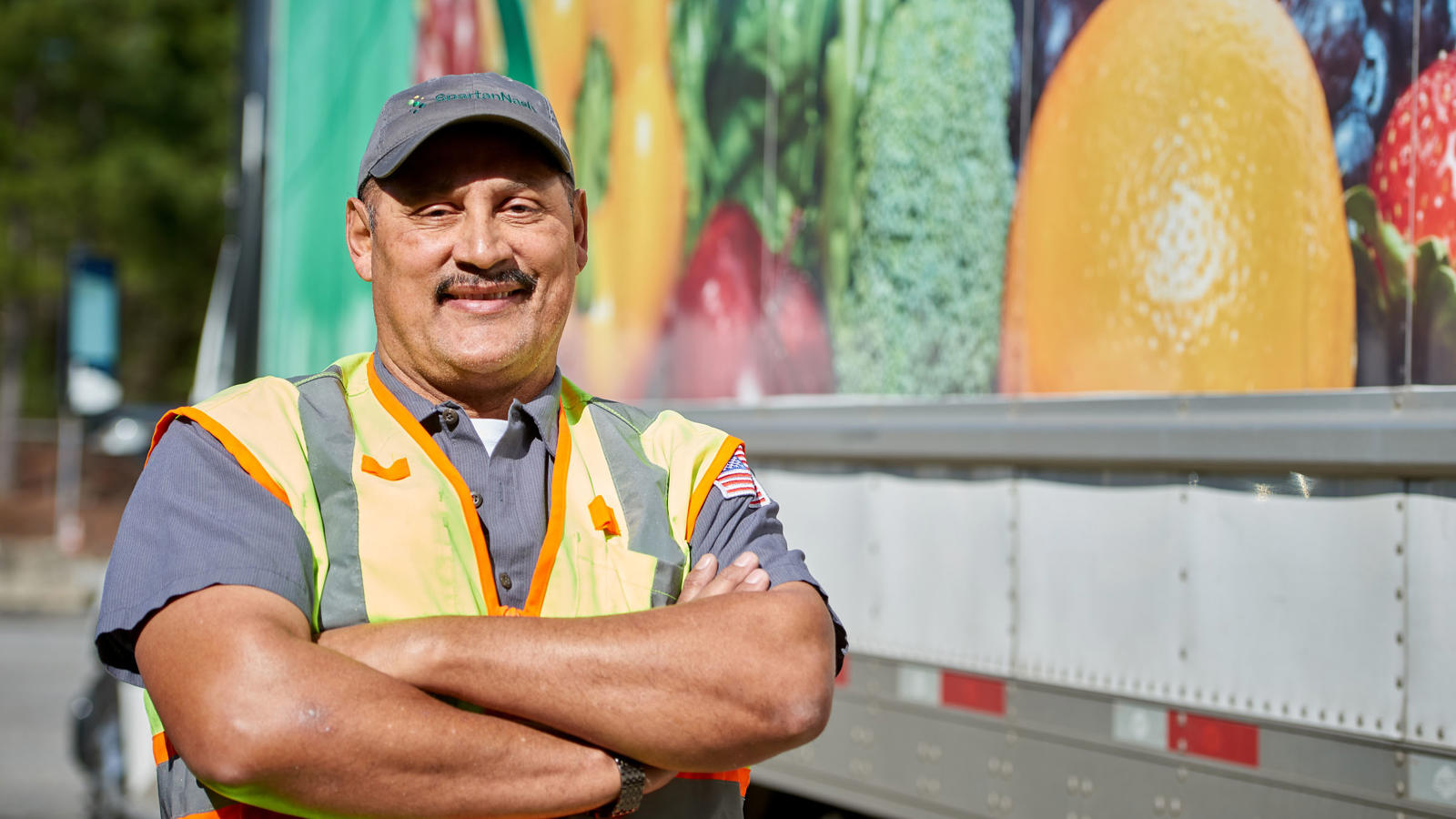 a man in a vest standing in front of a truck for SpartanNash