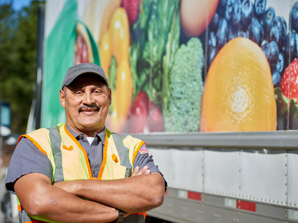 a man in a vest standing in front of a truck for SpartanNash