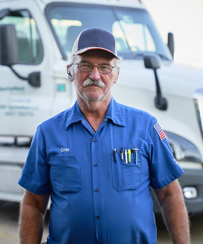 a man wearing a blue shirt and hat in front of a SpartanNash semi truck