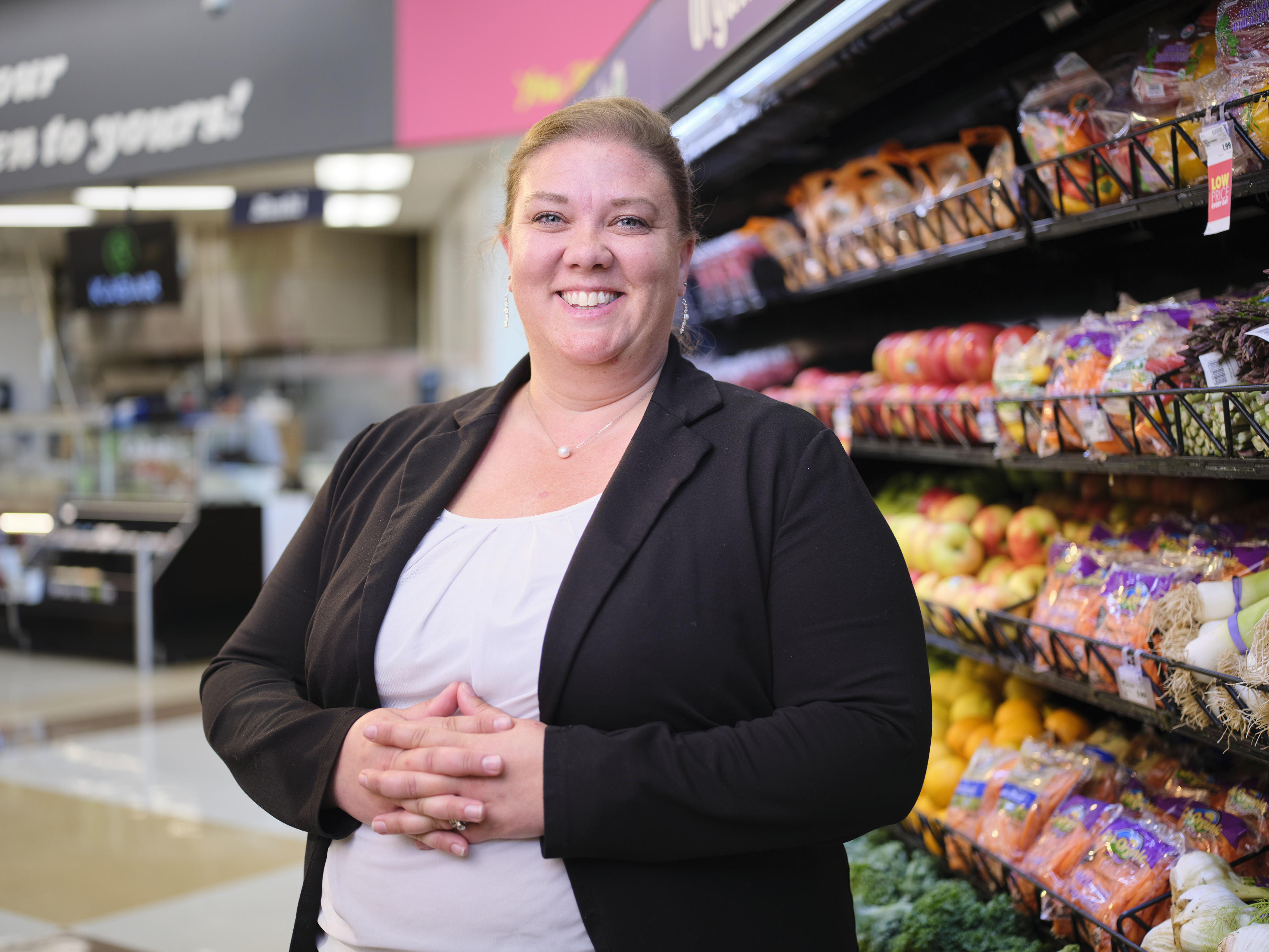 a woman standing in front of a shelf of produce