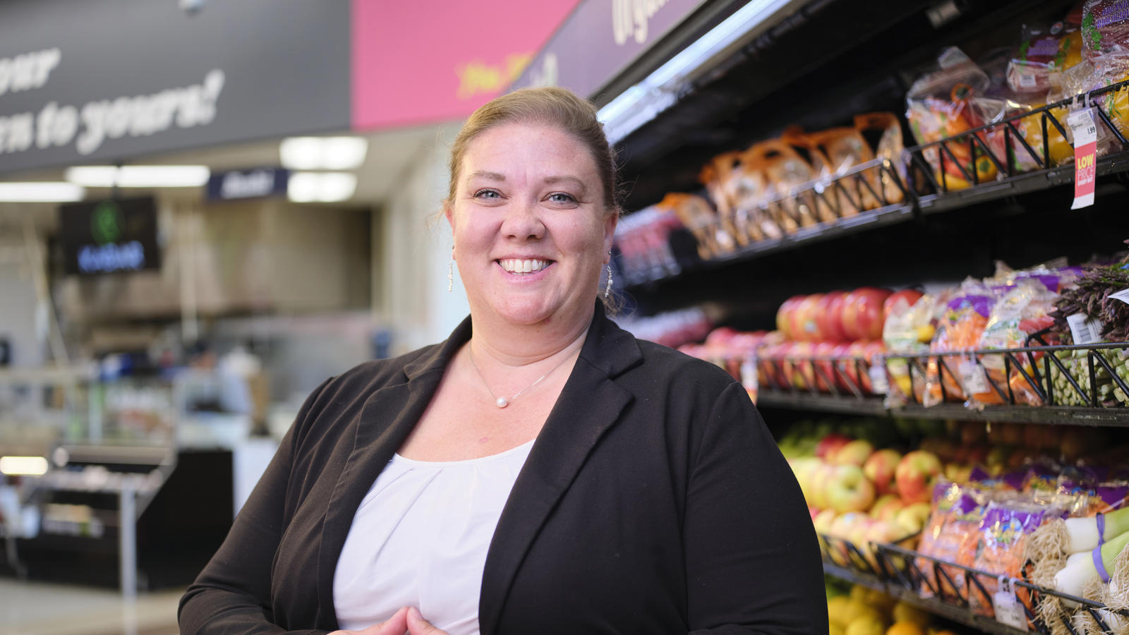 a woman standing in front of a shelf of produce
