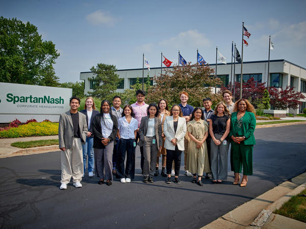 a group of interns standing in front of the corporate headquarters of SpartanNash