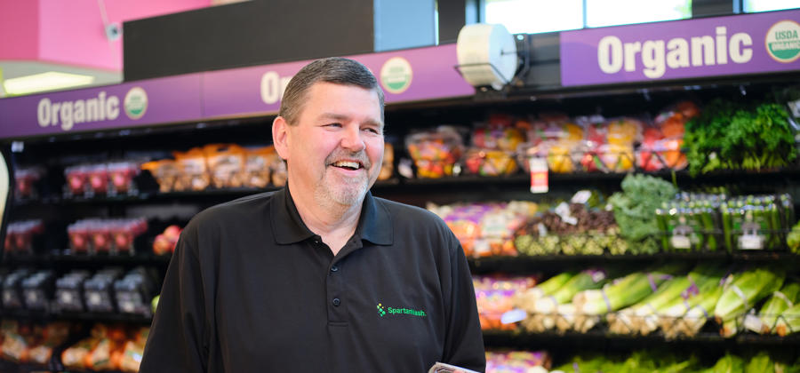 a man standing in a grocery store holding a container of food