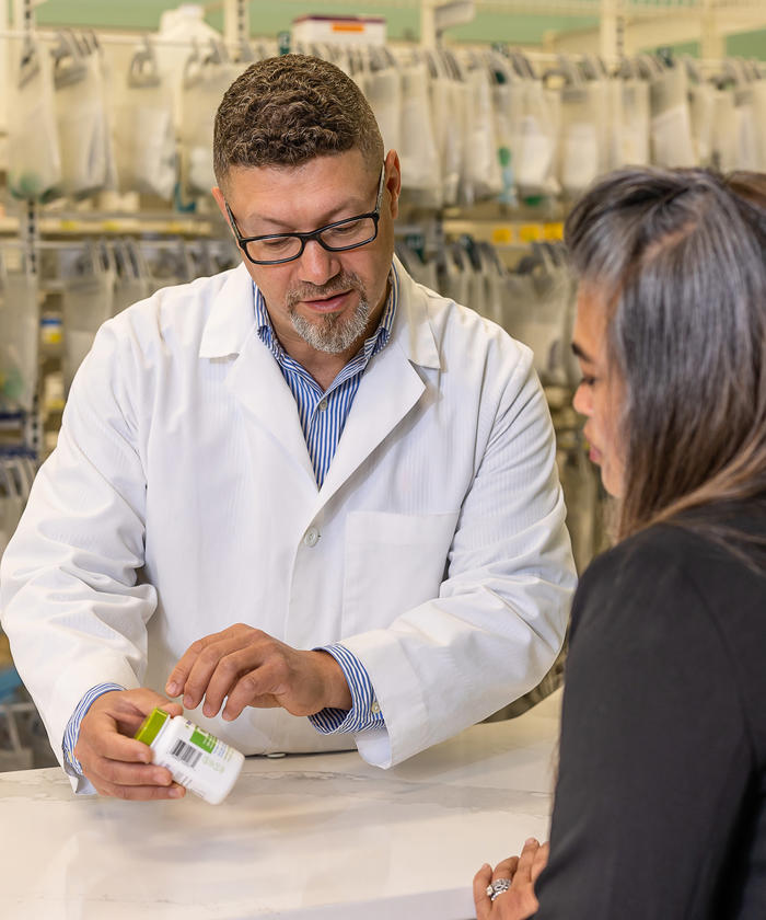 a man in a white coat holding a bottle of medicine at the Knapp pharmacy