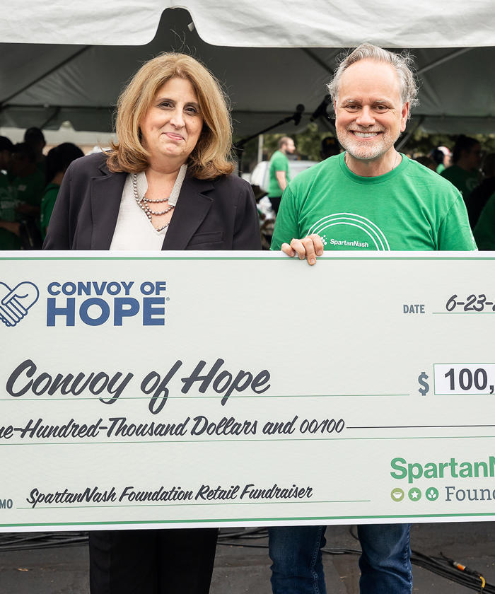 Tony Sarsam and woman holding a large check for Convoy of Hope