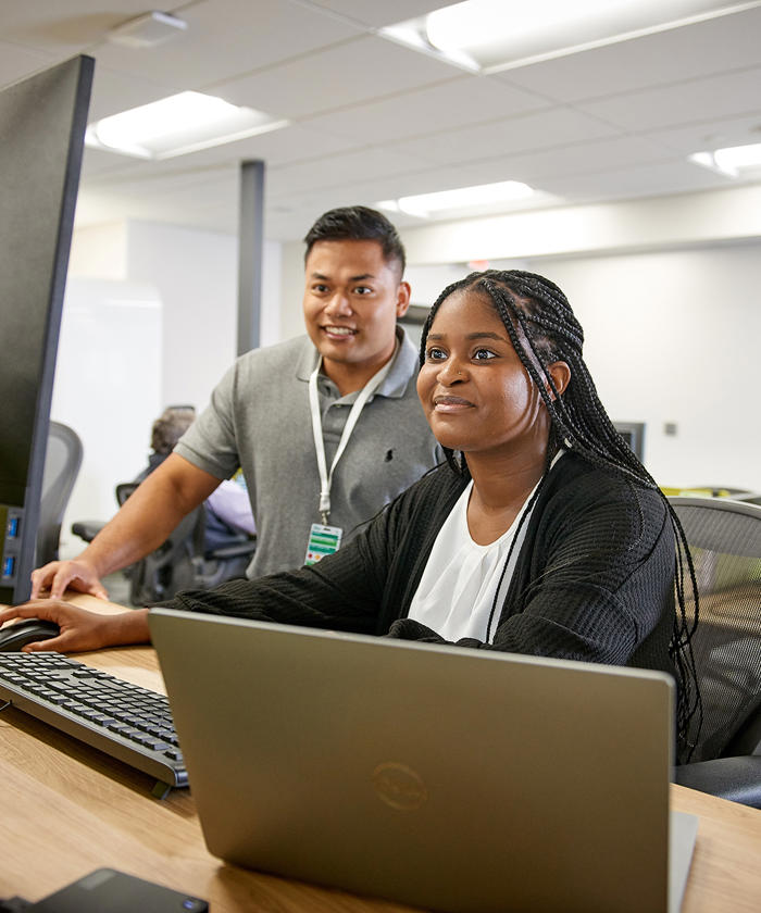 a man and woman sitting at a desk with computers
