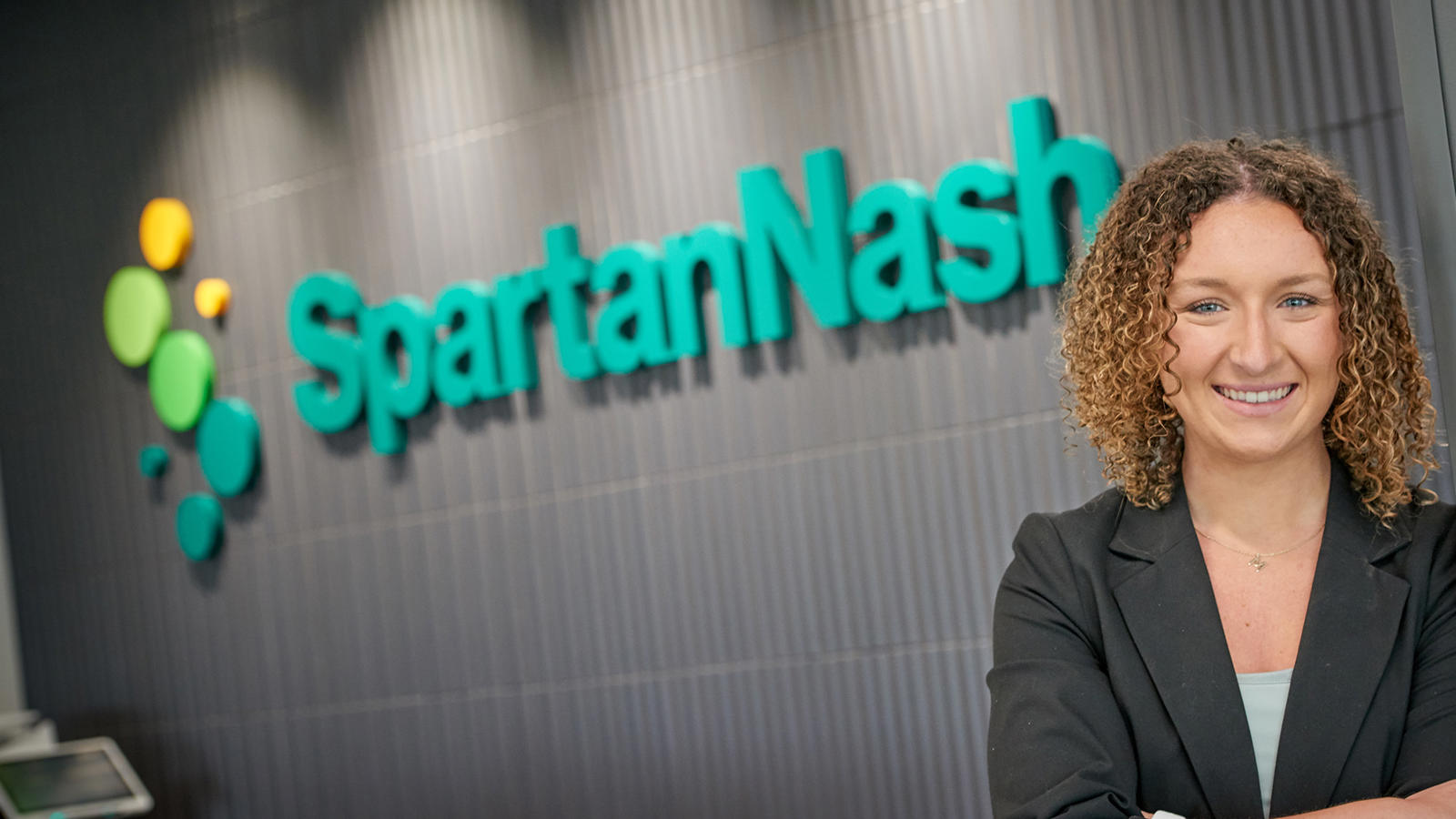 a woman standing in front of a SpartanNash sign