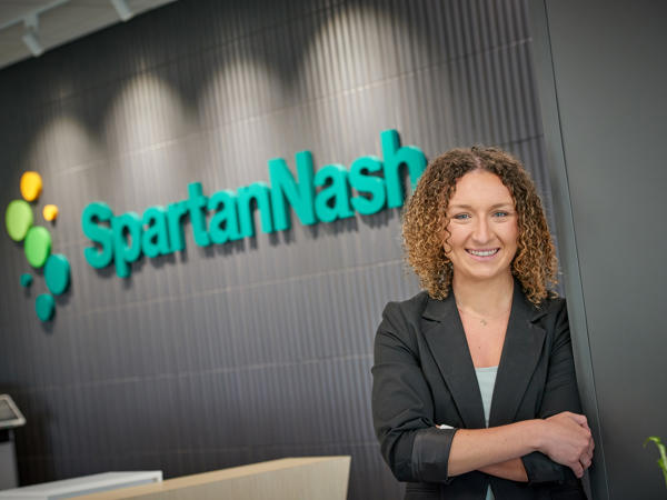 a woman standing in front of a SpartanNash sign