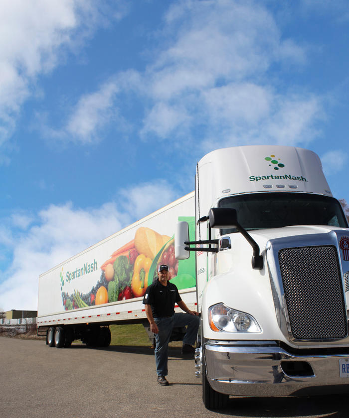 a man standing next to a SpartanNash truck